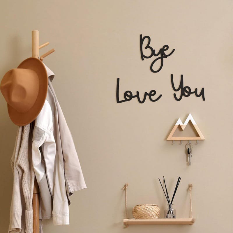Wooden coat rack with hat and jacket, wall decor reading "Bye Love You", and key holder.