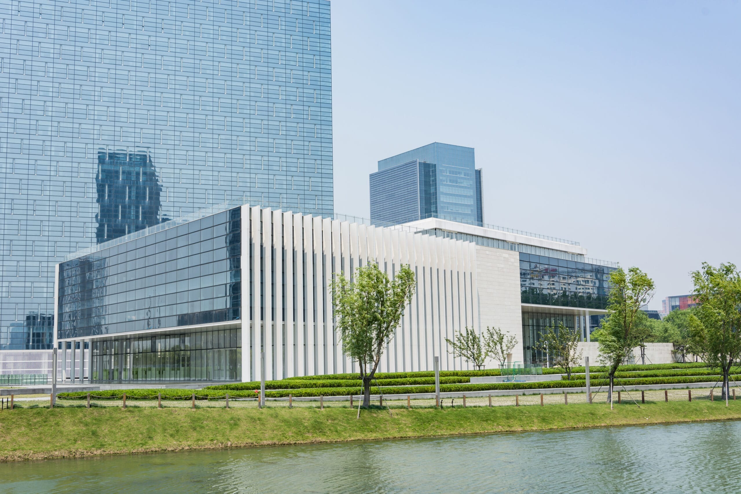 Modern glass and stone office building near a pond