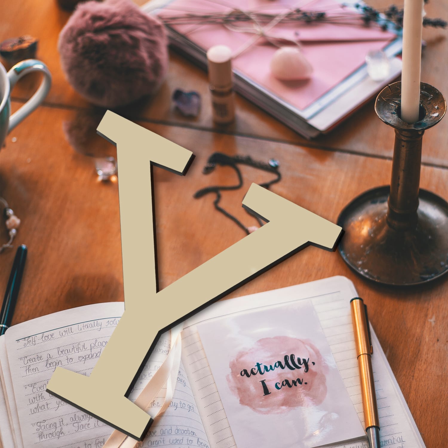 Journal with "actually, I can" affirmation, candles, and crystals; self-care and positive affirmation concept.